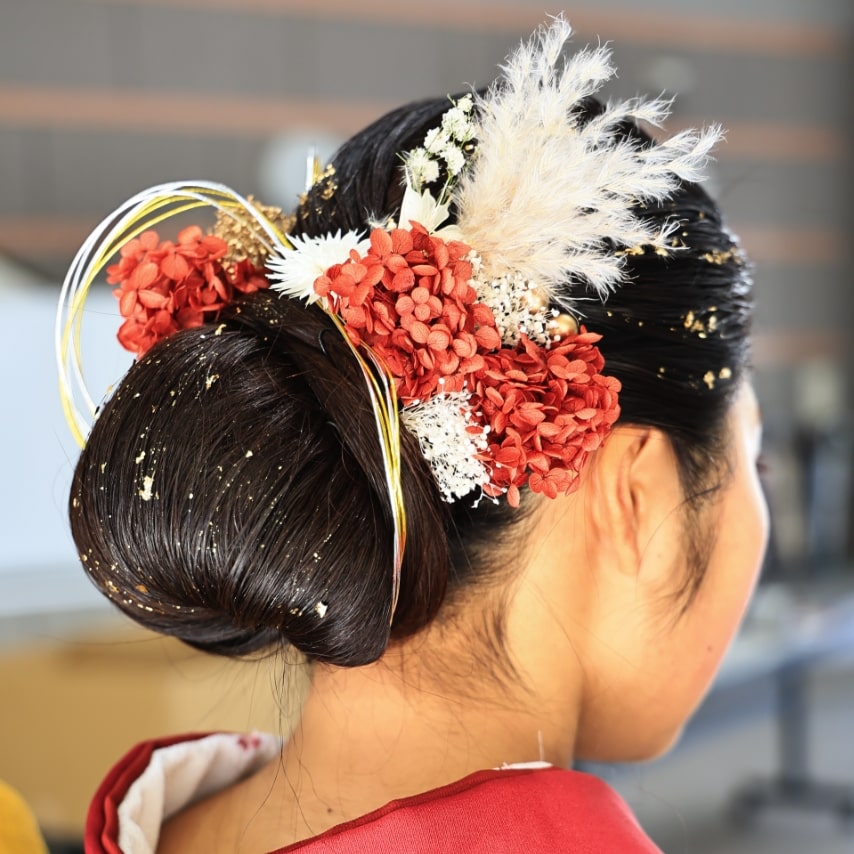 たっぷりボリュームのまとめ髪。振袖の色に合わせた花々と水引を飾って。個性的かつ、きちんとした印象。