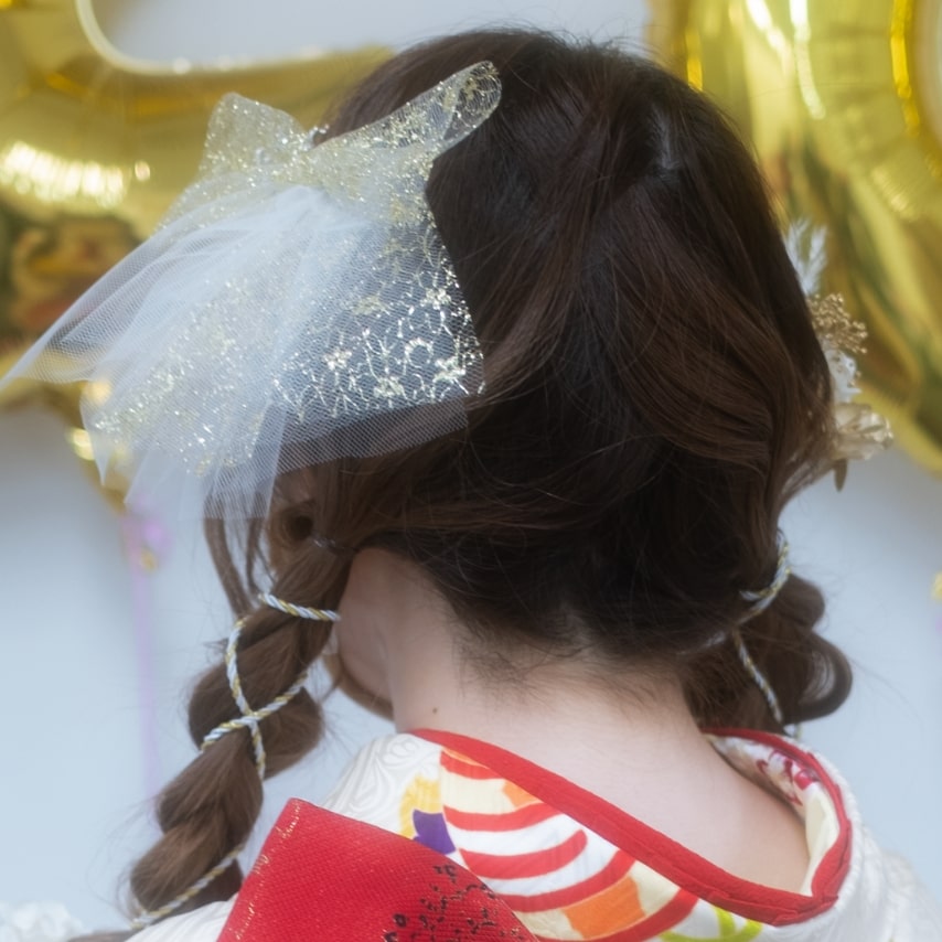 エアリーなリボンが印象的。三つ編みは紐を巻き付けて華やかさアップ。少女っぽいキュートなヘアスタイル。