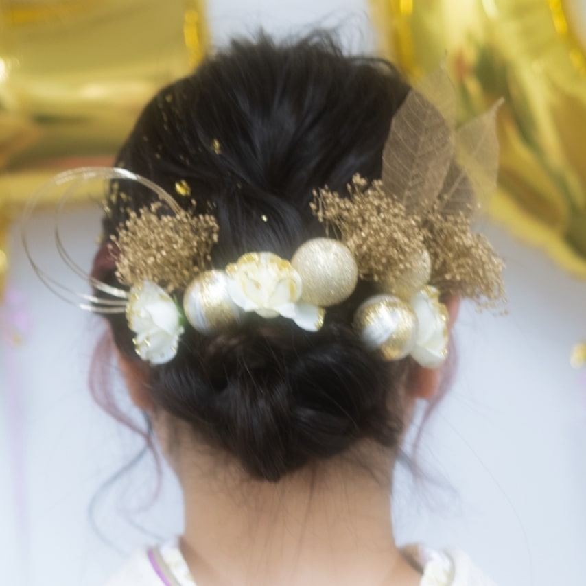 和玉や花、水引などさまざまな素材をミックスした髪飾り。白とゴールドの2色づかいがエレガント。