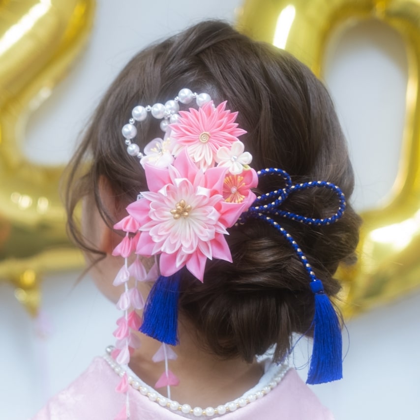 振袖に合わせて髪飾りもピンクのちりめん細工をセレクト。鮮やかな青の組紐が洗練された印象を作る。
