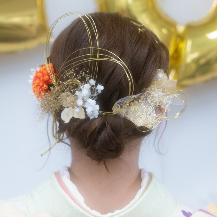 シンプルなローシニヨンに小花を飾ってフェミニンに。金の水引がさりげない華やかさを作ってくれる。