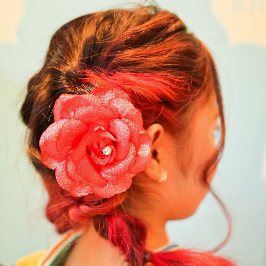 トップから編み込んで作るプリンセスを彷彿とさせるヘアアレンジ。インナーカラーを活かして髪飾りは大振りの花を一輪で。