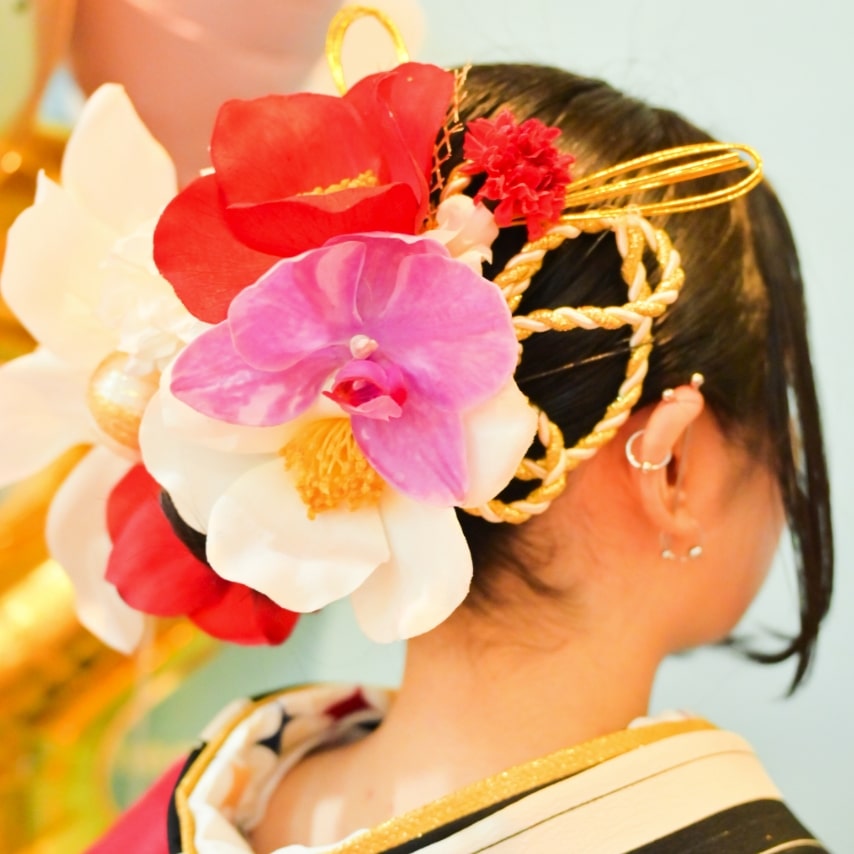 シニヨンを土台に大輪の紅白の椿や胡蝶蘭で一度きりの祝いの日を晴れ晴れしく彩りましょう。和紐や金箔でトレンド感もお忘れなく。