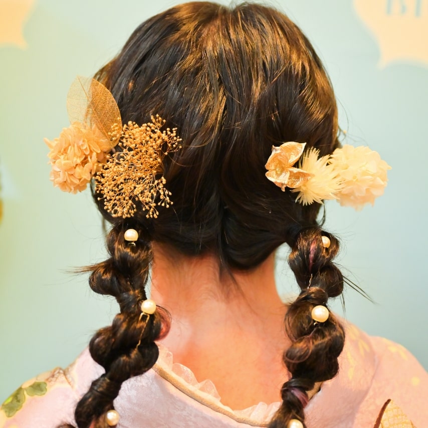 今らしいお下げスタイルにパールやドライフラワーで儚げな少女感のあるヘアアレンジ。ツインへの分け方もゆるくすることで和らげな印象へ。