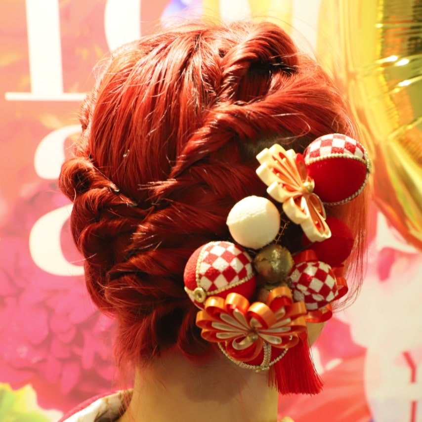 ビビッドなヘアカラーは成人式のような特別な日を鮮やかに彩ってくれます。細めのねじりアレンジでクールにまとめて、髪飾りも赤で揃えてインパクト大!