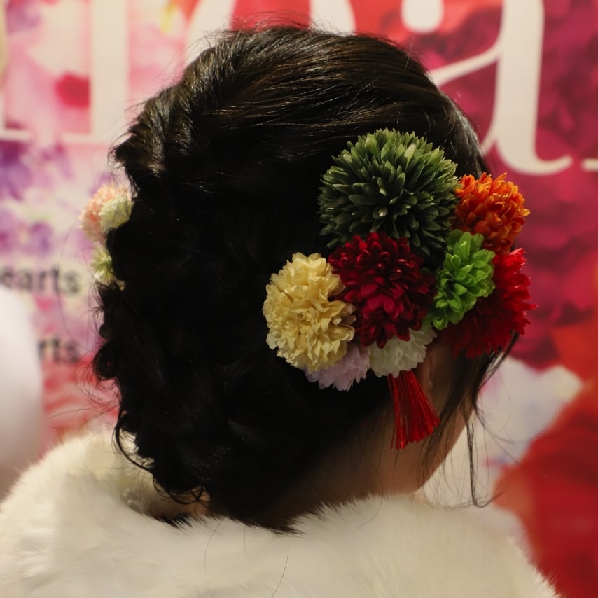 しっかり編み込んでまとめたヘアアレンジに、鮮やかな色とりどりの髪飾りで華やかに。タイトなまとめ髪はショールとも相性◎です!